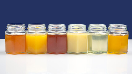 jars with different types and colors of honey on a white blue background. organic vitamin products