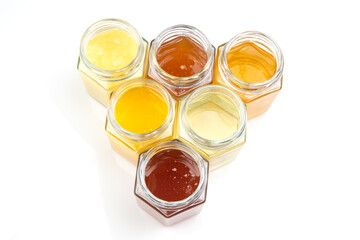 jars with different types and colors of honey on a white background. organic vitamin food