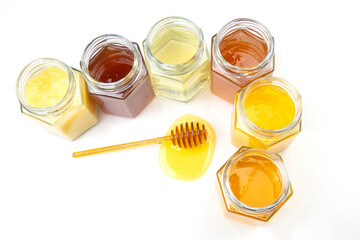 spoon with fresh honey and jars with different types of honey on a white background. organic vitamin food