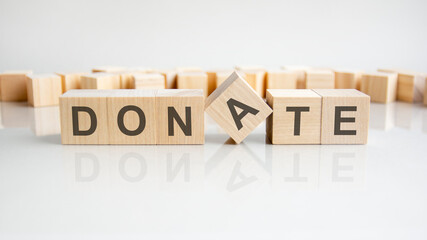 Donate text on a wooden blocks, gray background.