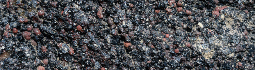 Closeup of aggregate rock of black volcanic rock and red rocks, as a nature background

