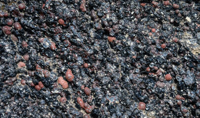 Closeup of aggregate rock of black volcanic rock and red rocks, as a nature background
