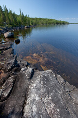 Gray stones and spruce and very blue water in the Scandinavian lake