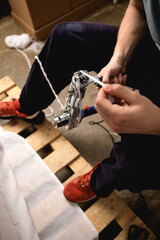 High angle view of craftsman pulling thread on rug tufting machine in workshop 