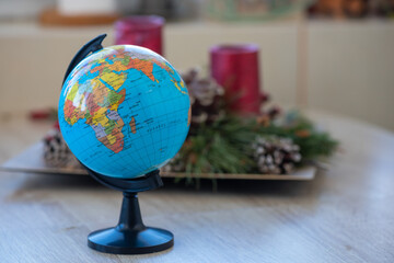 Toy globe on a wooden table with an advent in the background