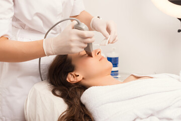 Obraz na płótnie Canvas Process of the ultrasound cleaning procedure for skin of the face, made in a white salon.