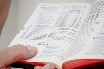 Bíblia sagrada aberta na mão e sendo folheada por pessoas.
