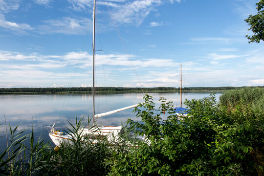 Blue sky covered with white clouds and sky reflection in the calm water of Pilka lake