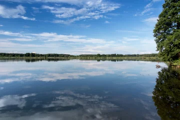 Foto op Canvas Blue sky covered with white clouds and sky reflection in the calm water of Pilka lake © rparys