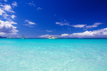 Tropical beach with turquoise water. Boats in the blue sea on Boracay island, Philippines.