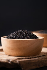 Black sesame seeds in a bowl on wooden with black background, Still Life