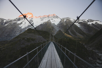 suspension bridge in newzealand at sunrise warm glow on the peaks