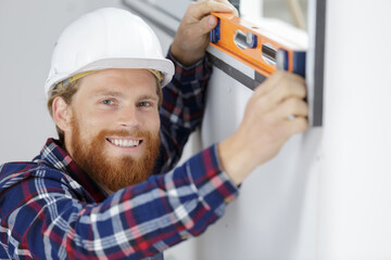 male worker taking measurements of window in flat