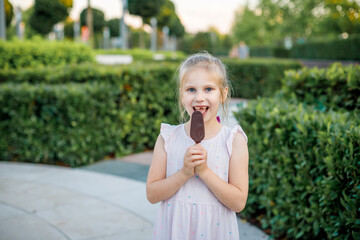 girl in a light dress eats popsicle ice cream in a city park. Children's rest in the summer.