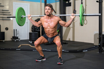 Fototapeta premium Strong men bodybuilder doing overhead with heavy barbell in modern gym. Functional training class. Bodybuilding and Fitness. High quality photo