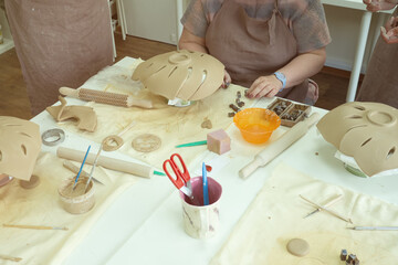 Woman hand potter making clay monstera leaf in pottery workshop studio. Process of creating ceramic vase. Handmade, hobby art and handicraft concept.