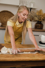 Beautiful woman baker or housewife rolls the dough with a rolling pin. Chef profession concept