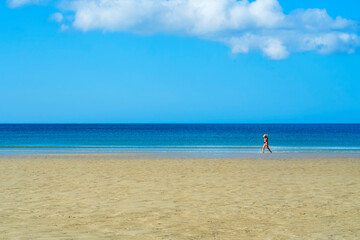 Mujer con bikini rojo paseando por una playa de Galicia