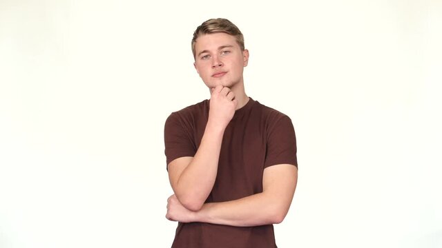 Footage of young causal man standing over white background and thinking.