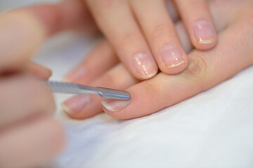 Obraz na płótnie Canvas manicurist filing persons nails in salon