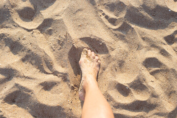 Female slender leg on golden sand. Rest on the seaside