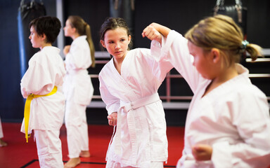 Focused preteen girls practicing new karate moves in pairs at sport gym