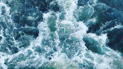 Picturesque top view to the turquoise sea waves strongly colliding with each other and creating beautiful foam and splashes in motion.