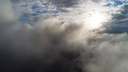 Amazing flight through moving clouds towards bright shining sun. View from airplane window to beautiful evening cloudscape.