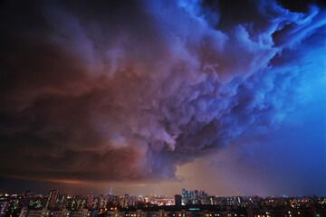 Amazing view of the night storm over the big city, with colorful clouds moving on the sky and...