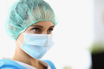 The female doctor wears a protective mask and cap