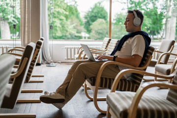 In the hands of a laptop to surf the Internet. A college student listens to an audiobook with wireless headphones. Online training using the app.