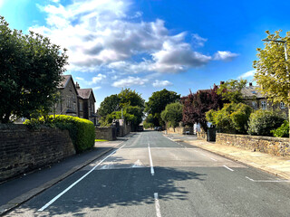 View down, Ashfield Road, with trees, houses, and a blue sky near, Saltaire, Bradford, UK