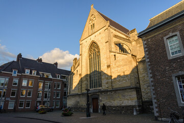 Outdoor sunny street view of Oude Minderbroederskerk, Catholic church, in old town Maastricht, Netherlands during sunset time.
