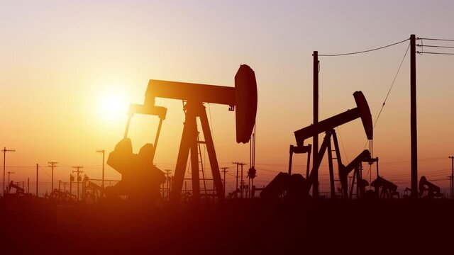 The sun rises behind oil pumps in California