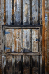 Weathered exterior wall with a small wooden hatch, as a rustic background
