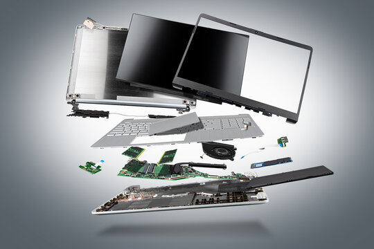 flying parts of a notebook computer. hardware components mainboard cpu processor display RAM cables and cooling fan flying out of silver laptop PC case dark gray exploded view background