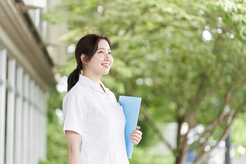 緑背景で笑顔で立つ看護師