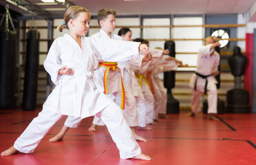 Preteen girl wearing in kimono attempting to master new moves in sport gym