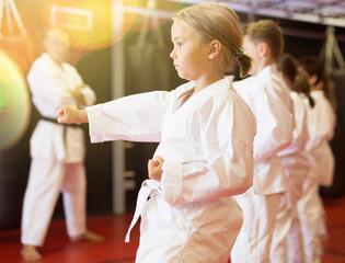 Portrait of girl kid training karate movements in sport class in school