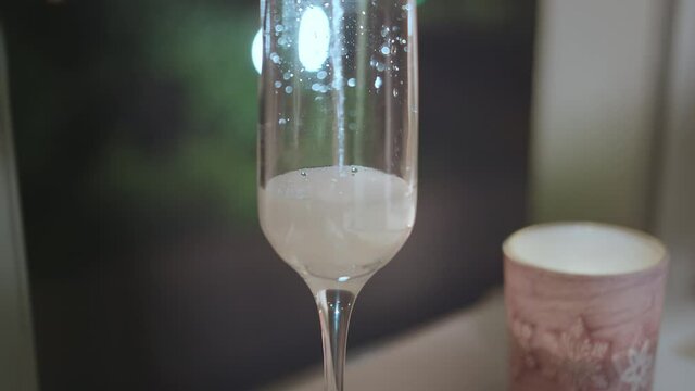 Champagne fill a glass next to a candle stands, night lights background