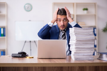 Young male employee unhappy with excessive work in the office