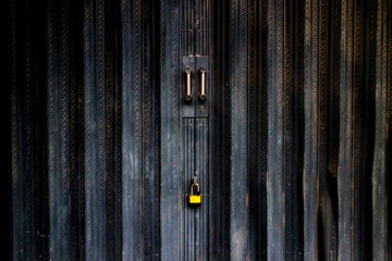 yellow padlock on black metal folding gate.