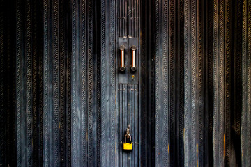 yellow padlock on black metal folding gate.