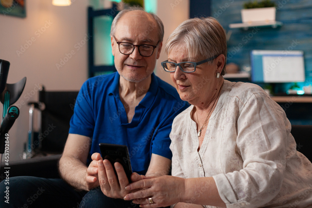 Poster senior family of two looking at smartphone screen display using modern technology device to browse i