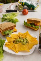 details of sandwiches prepared with fresh ingredients, armed with whole wheat bread, cheese, lettuce and a plate with nachos on a table, delicious food prepared at home, snack