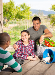 Young farmers talking while sitting at table in the garden