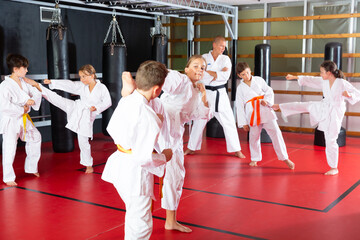 Adolescent boys and girls in kimono fighting with each other in gym.