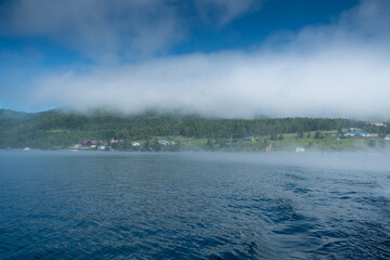 Fototapeta na wymiar Lake Baikal close to village Port Baikal, Russia. Sunny day view of the high shore and clear lake water with fog