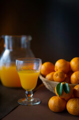glass with orange juice (oranges and tangerines in the background)
