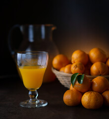 glass with orange juice (oranges and tangerines in the background)